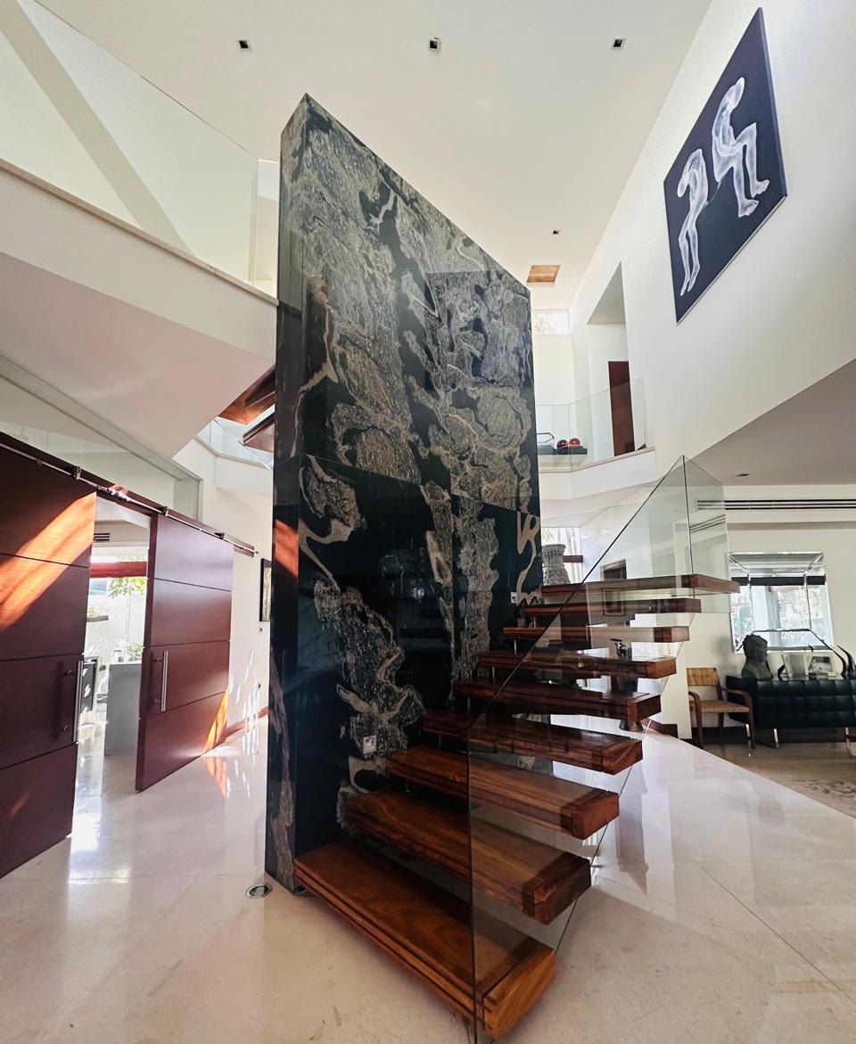 Vestíbulo de doble altura con escalera escultórica de madera y piedra