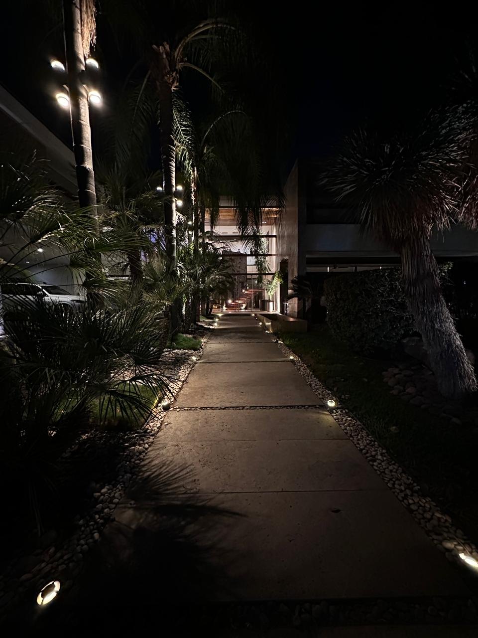 Andador iluminado hacia el acceso principal por la noche
